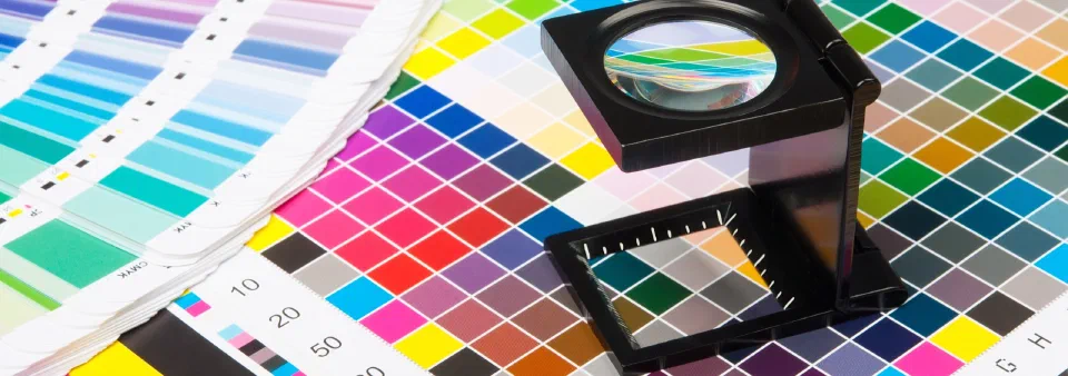 A printer's colour fan and loupe on a press sheet of colour patches
